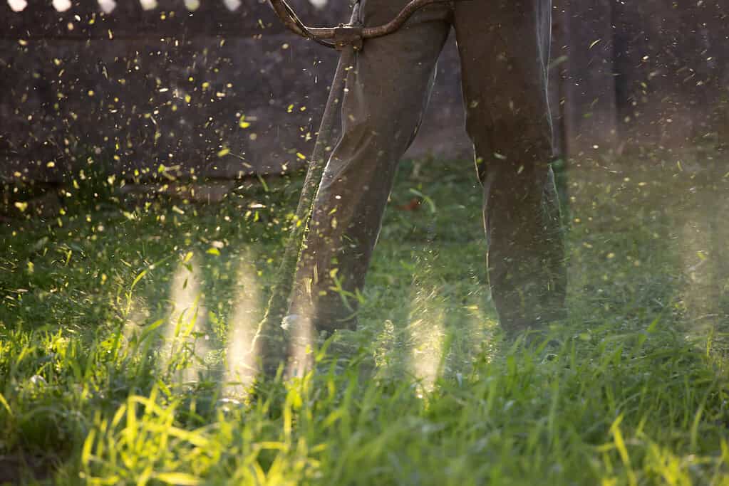 Tractor tilling soil in a lush green field at sunset, showcasing durable equipment for farm and outdoor work by McFarland Outdoors.